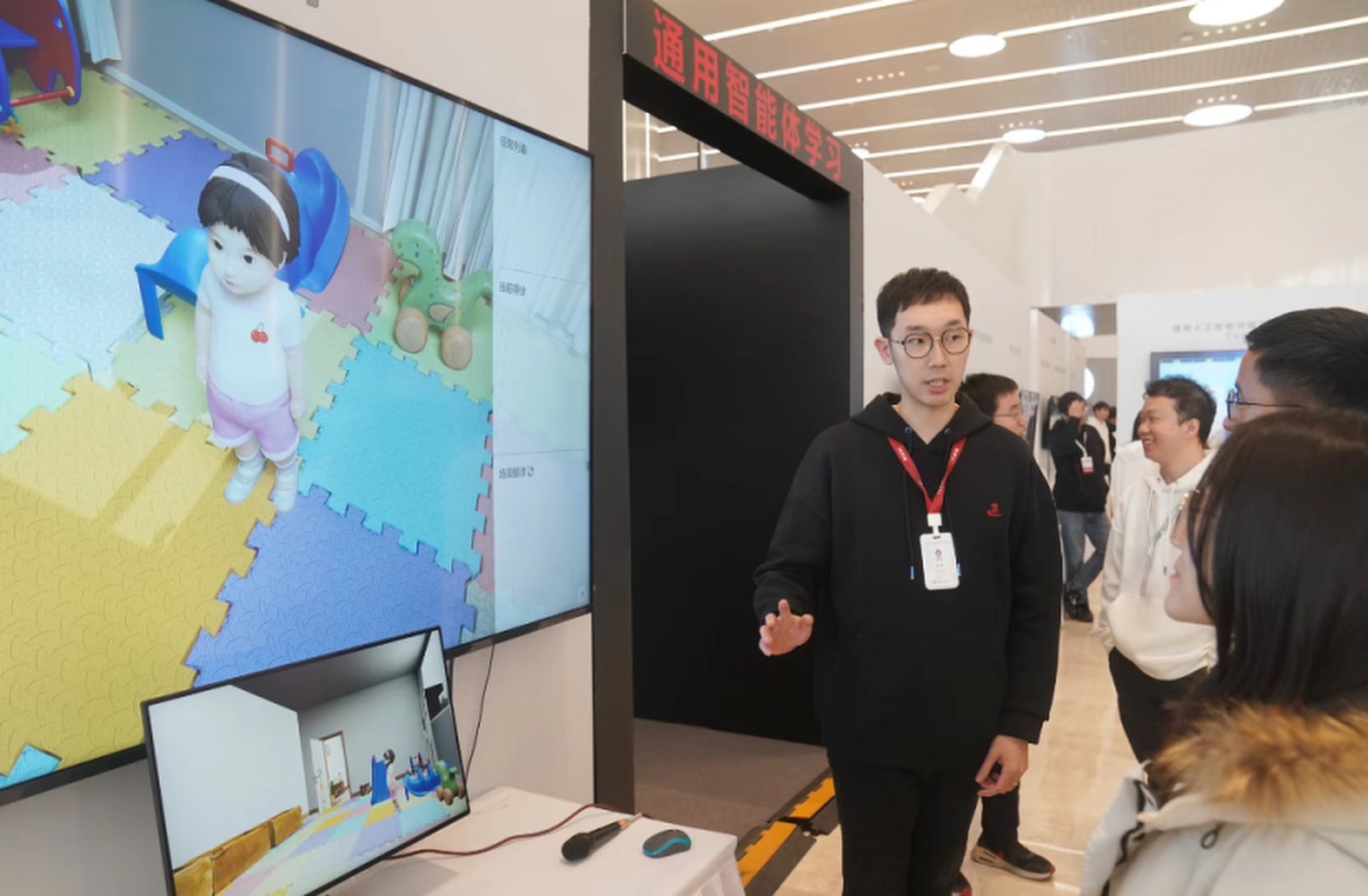 A researcher from the  Beijing Institute for General Artificial Intelligence explains how to interact with Tong Tong at the Frontiers of General Artificial Intelligence Technology Exhibition in Beijing in late January. Photo: bjd.com